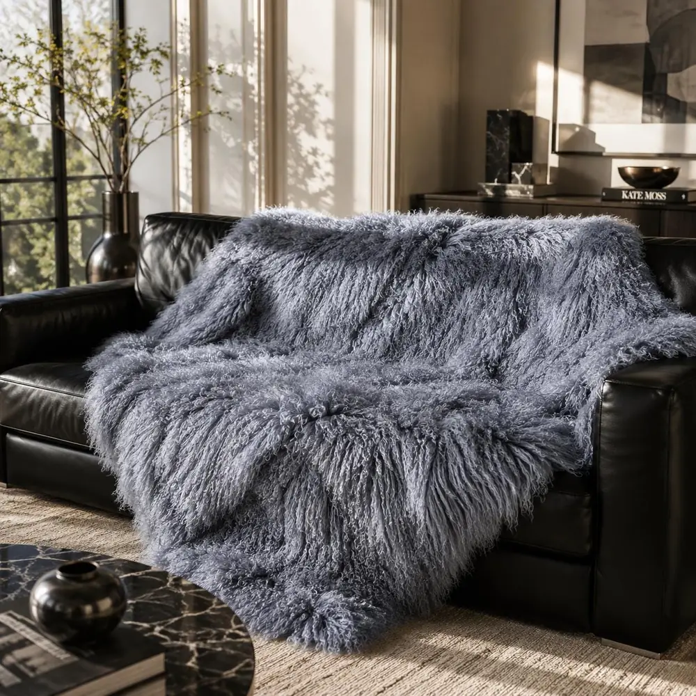 Grey Tibetan lambskin throw draped over a black leather sofa